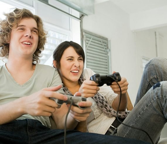 Teenage couple playing with games consoles